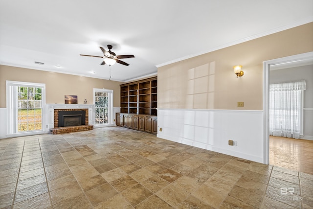 unfurnished living room with a fireplace, ceiling fan, and ornamental molding