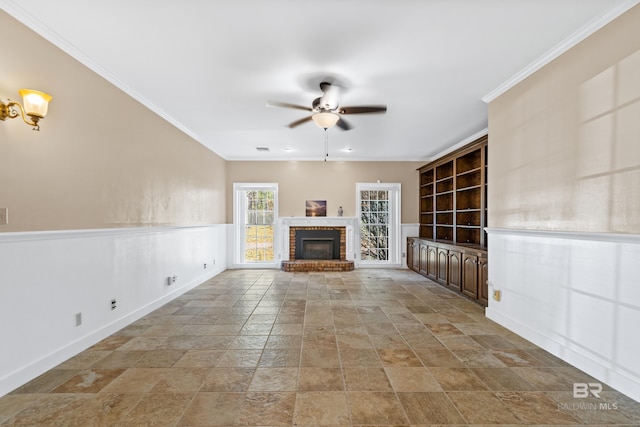 unfurnished living room with a brick fireplace, ceiling fan, and crown molding