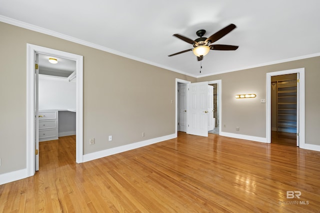 unfurnished bedroom featuring light hardwood / wood-style floors, ornamental molding, ceiling fan, a spacious closet, and a closet