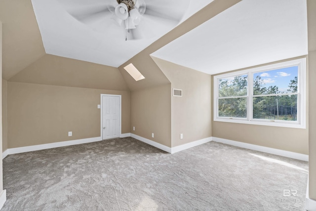 bonus room with vaulted ceiling with skylight, light carpet, and ceiling fan