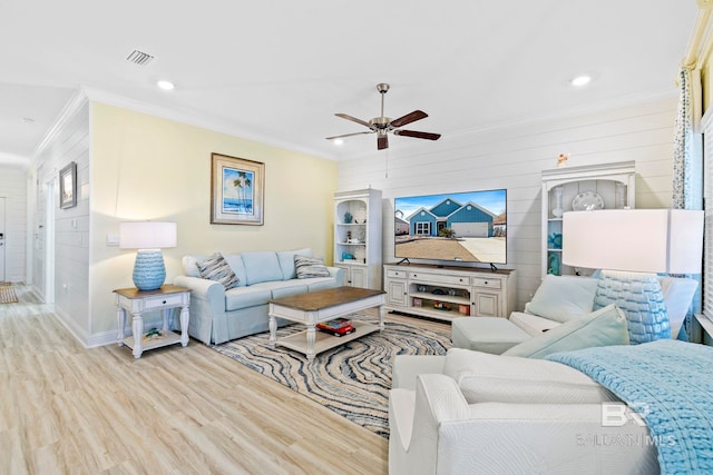 living room featuring ornamental molding, wood walls, and light hardwood / wood-style flooring