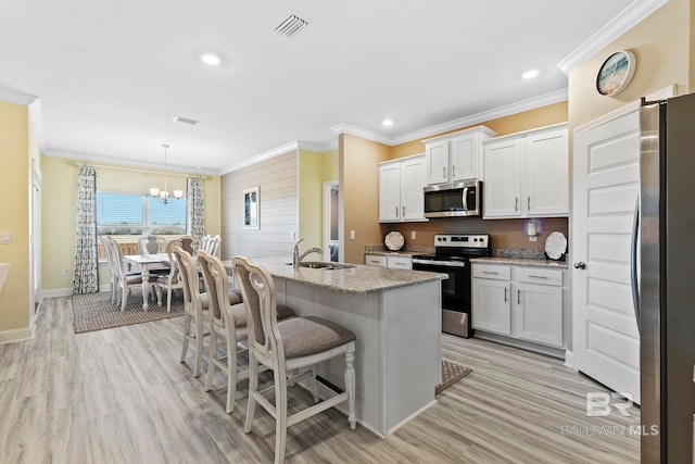 kitchen featuring stainless steel appliances, white cabinetry, sink, and decorative light fixtures