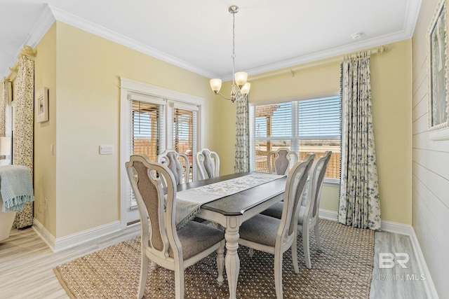 dining area featuring crown molding, a notable chandelier, and light hardwood / wood-style flooring