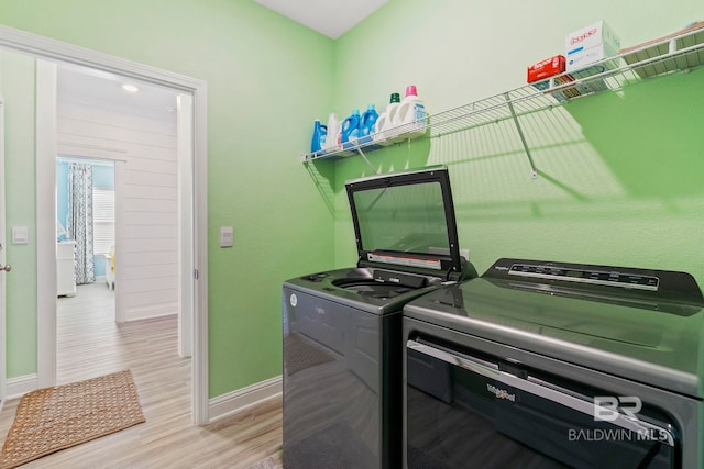 laundry area with light hardwood / wood-style flooring and washer and dryer