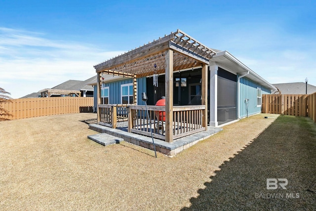 rear view of property featuring a wooden deck, a yard, a pergola, and a sunroom