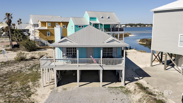 rear view of property with a carport, a water view, metal roof, and driveway