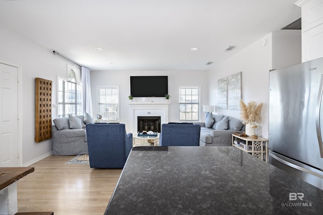 living room with light wood-type flooring, a fireplace, visible vents, and recessed lighting