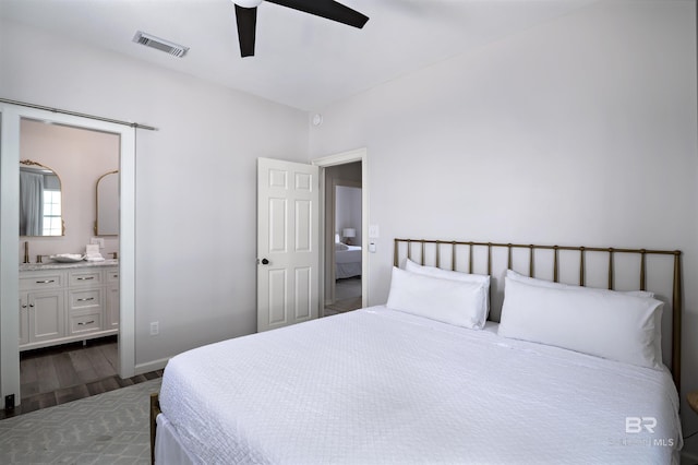 bedroom with dark wood-style floors, visible vents, ceiling fan, and ensuite bathroom