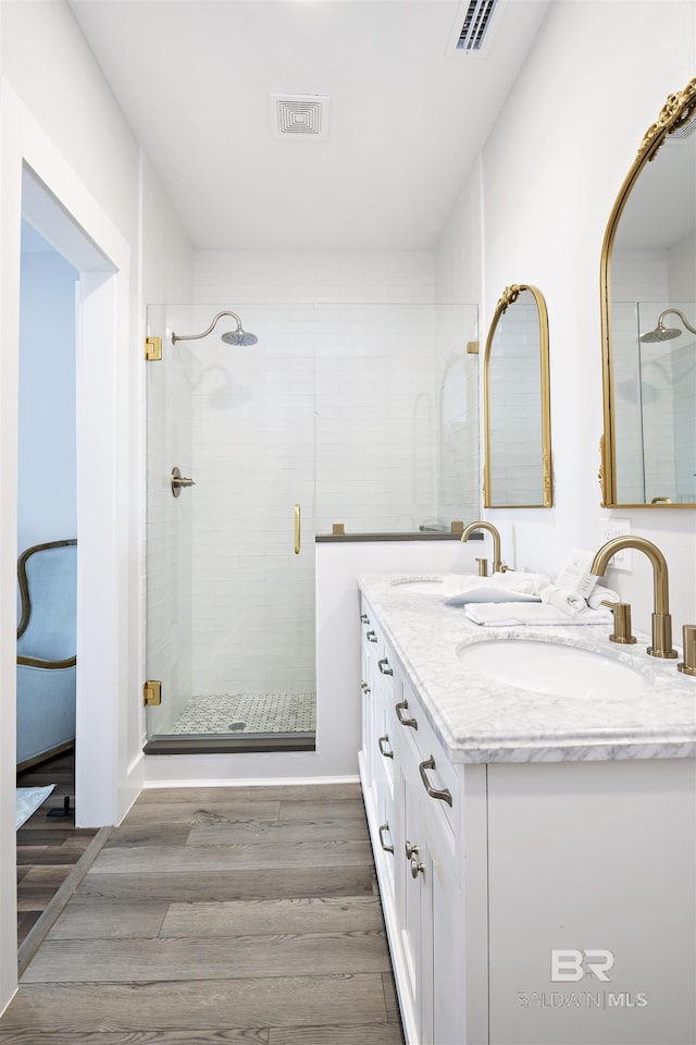 full bathroom with a stall shower, visible vents, a sink, and wood finished floors