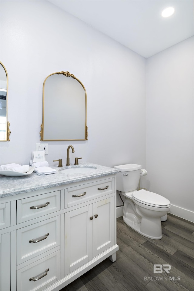 bathroom with baseboards, vanity, toilet, and wood finished floors