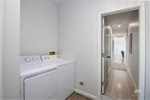 washroom with washing machine and dryer, laundry area, light wood finished floors, and baseboards