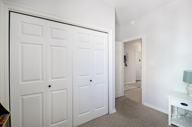 carpeted bedroom featuring a closet and baseboards