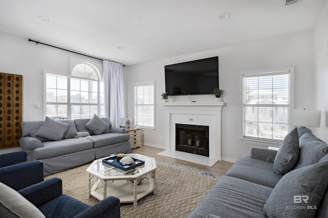 living room featuring recessed lighting, a fireplace, visible vents, and light wood-style floors