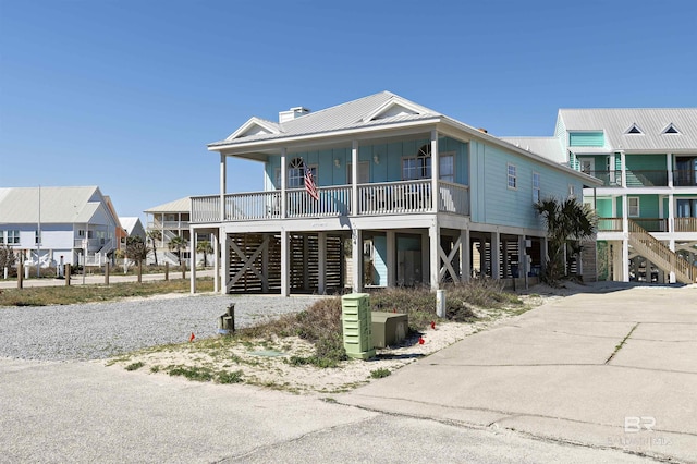 beach home featuring a porch, driveway, a residential view, a carport, and board and batten siding