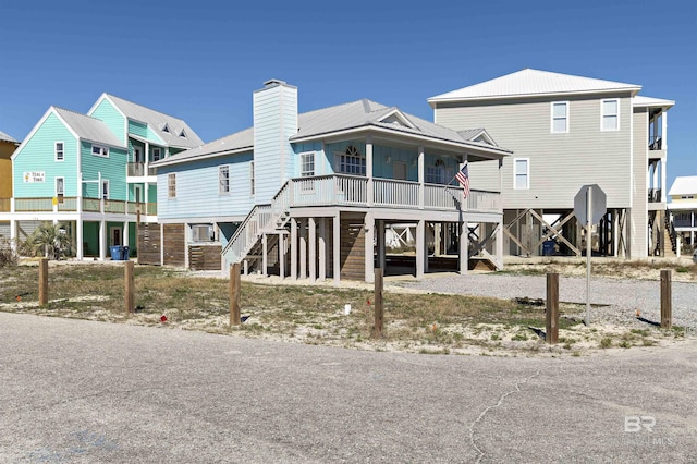 view of front facade featuring covered porch, a carport, stairway, and a chimney