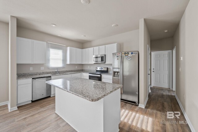 24154 Veranda Cir, Elberta, AL 36530 - kitchen featuring appliances with stainless steel finishes, a sink, white cabinets, light wood-type flooring, and a kitchen island