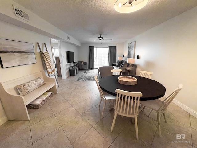 dining room with baseboards, visible vents, a textured ceiling, and a ceiling fan