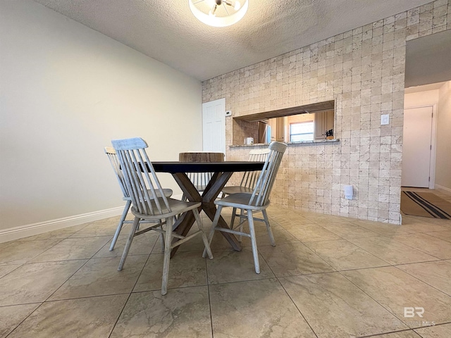 dining space featuring baseboards, a textured ceiling, and tile patterned flooring