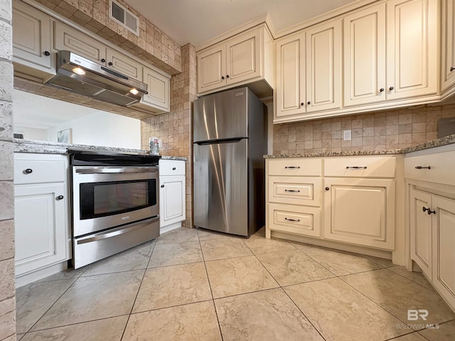 kitchen with under cabinet range hood, visible vents, cream cabinetry, and appliances with stainless steel finishes