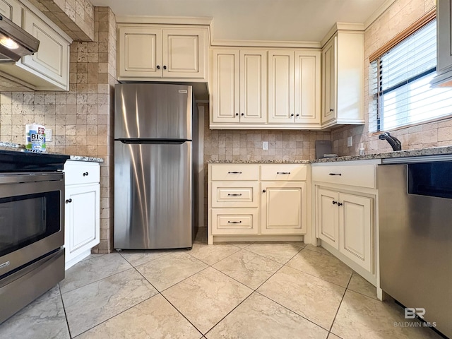 kitchen featuring light stone counters, cream cabinets, stainless steel appliances, and exhaust hood