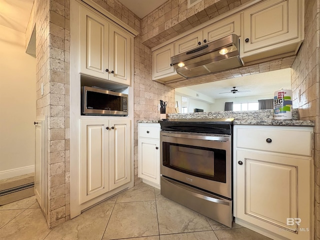 kitchen with cream cabinetry, a ceiling fan, under cabinet range hood, light stone counters, and stainless steel appliances