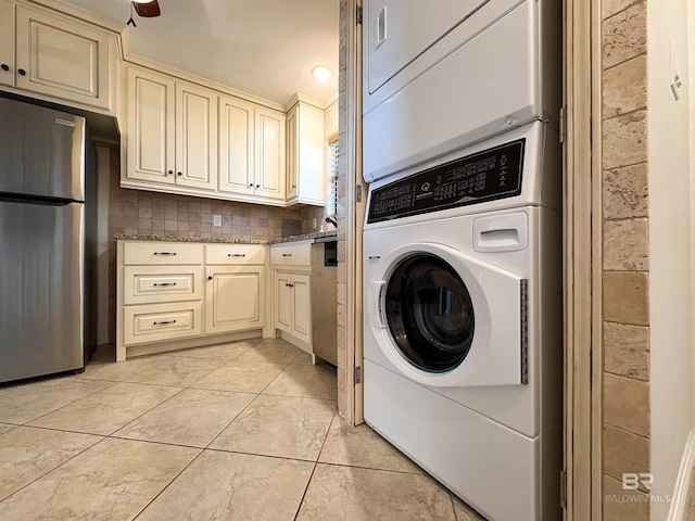 laundry area with laundry area, stacked washer / dryer, and light tile patterned floors