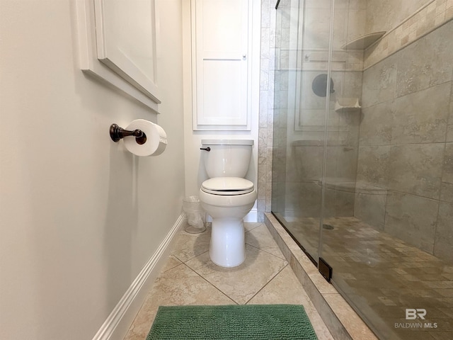 bathroom featuring tile patterned flooring, toilet, baseboards, and a stall shower