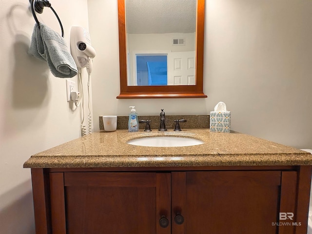 bathroom with visible vents, a textured ceiling, and vanity