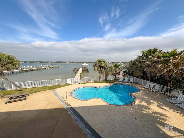 community pool with fence, a patio, and a water view