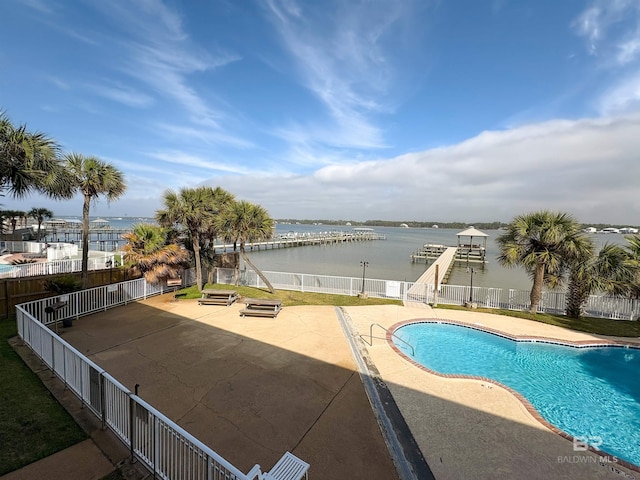 community pool featuring a patio area, fence, and a water view