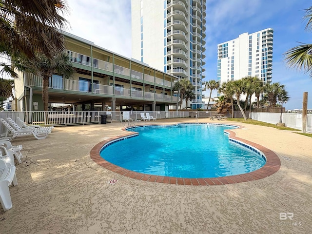 pool with a patio area and fence