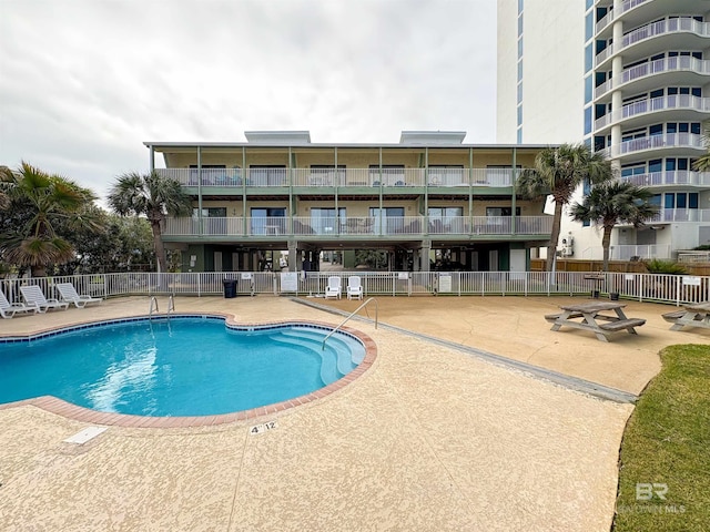 pool with a patio area and fence