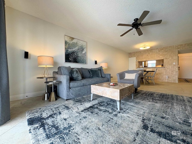 living room featuring a textured ceiling, baseboards, brick wall, and ceiling fan