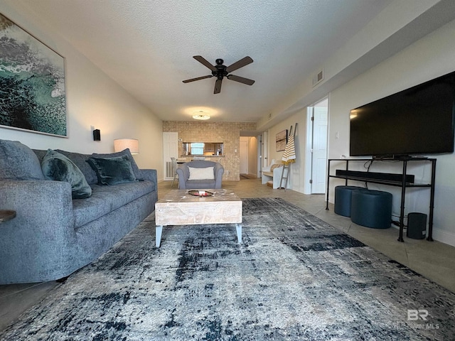 tiled living room featuring a textured ceiling, baseboards, visible vents, and ceiling fan