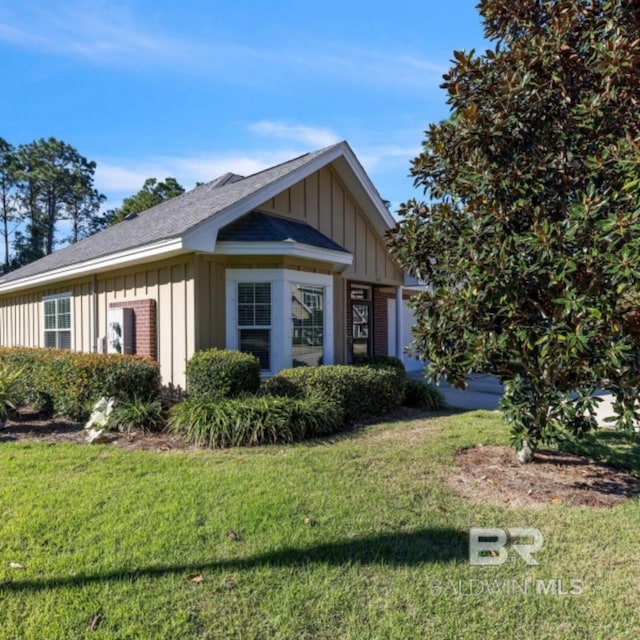 430 W Fort Morgan Rd Unit 1401, Gulf Shores, AL 36542 - view of front of house with board and batten siding, a front yard, brick siding, and a shingled roof