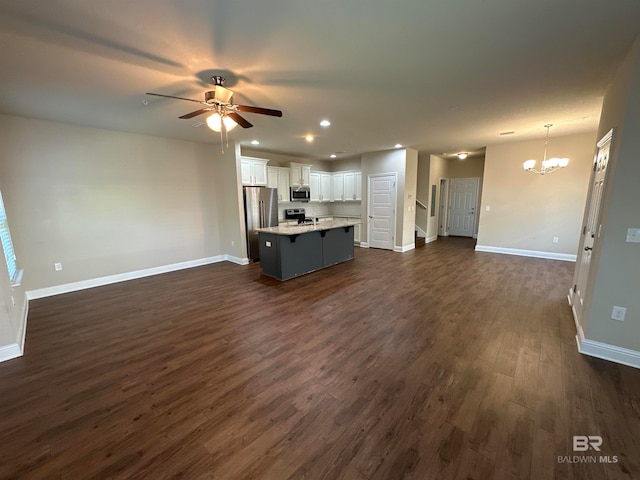 unfurnished living room featuring dark wood-type flooring and ceiling fan with notable chandelier