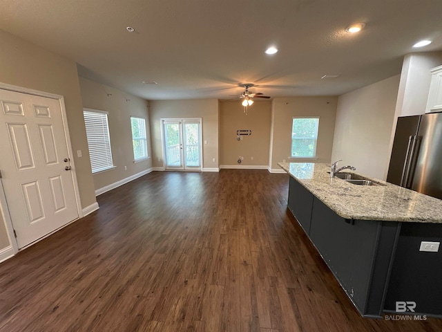 kitchen featuring sink, a spacious island, white cabinetry, light stone counters, and dark hardwood / wood-style floors