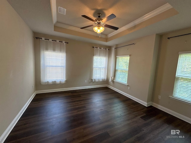 spare room with dark hardwood / wood-style floors, a tray ceiling, and plenty of natural light