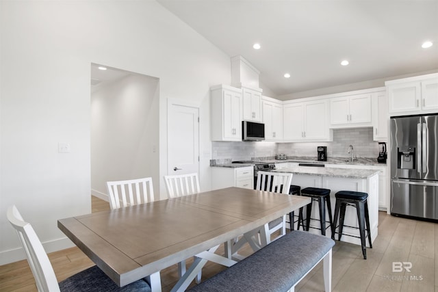 dining space with lofted ceiling, light wood-style flooring, baseboards, and recessed lighting