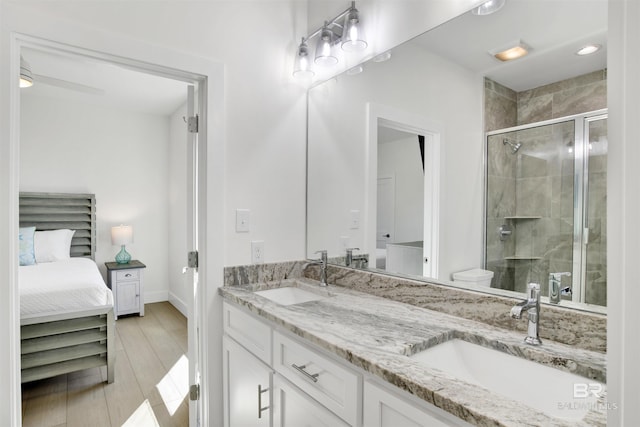 bathroom featuring double vanity, a stall shower, a sink, and wood finished floors