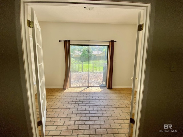 spare room with baseboards and brick floor