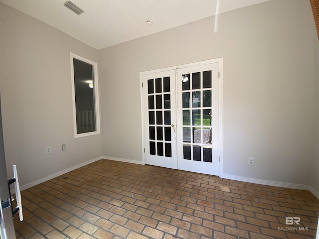 spare room with baseboards, french doors, visible vents, and brick floor