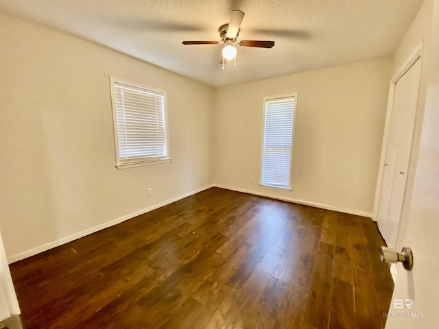 unfurnished bedroom featuring baseboards, dark wood finished floors, and ceiling fan