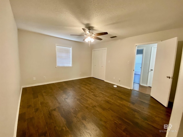 empty room with dark wood finished floors, visible vents, baseboards, a textured ceiling, and ceiling fan