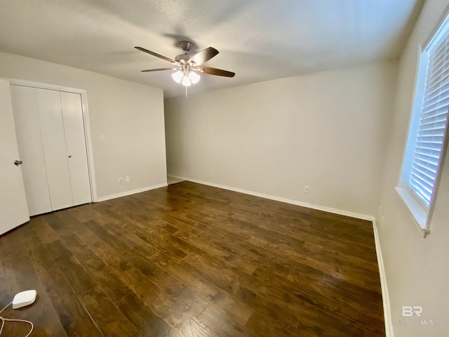 unfurnished bedroom with dark wood-style flooring, baseboards, and ceiling fan