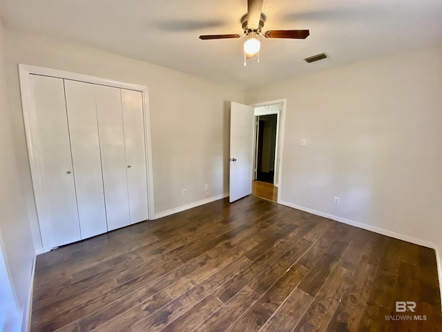unfurnished bedroom featuring a closet, baseboards, ceiling fan, visible vents, and dark wood-type flooring