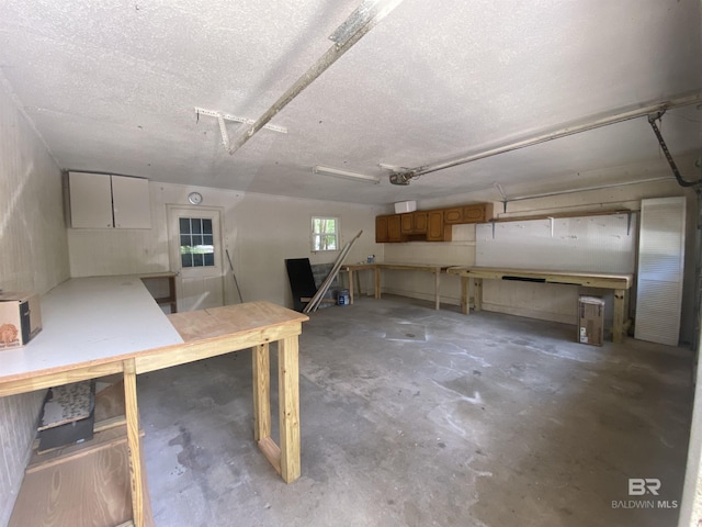 basement featuring a workshop area, a garage, and a textured ceiling