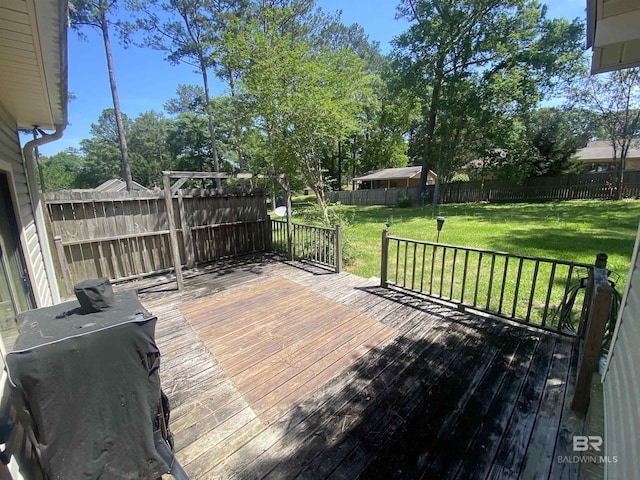 wooden deck featuring area for grilling, a yard, and a fenced backyard
