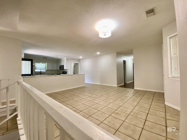 unfurnished room with a sink, a textured ceiling, visible vents, light tile patterned flooring, and recessed lighting