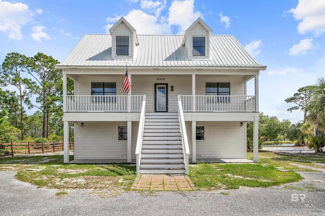 26498 Carondelette Dr, Orange Beach, AL 36561 - raised beach house featuring stairway, metal roof, fence, and covered porch